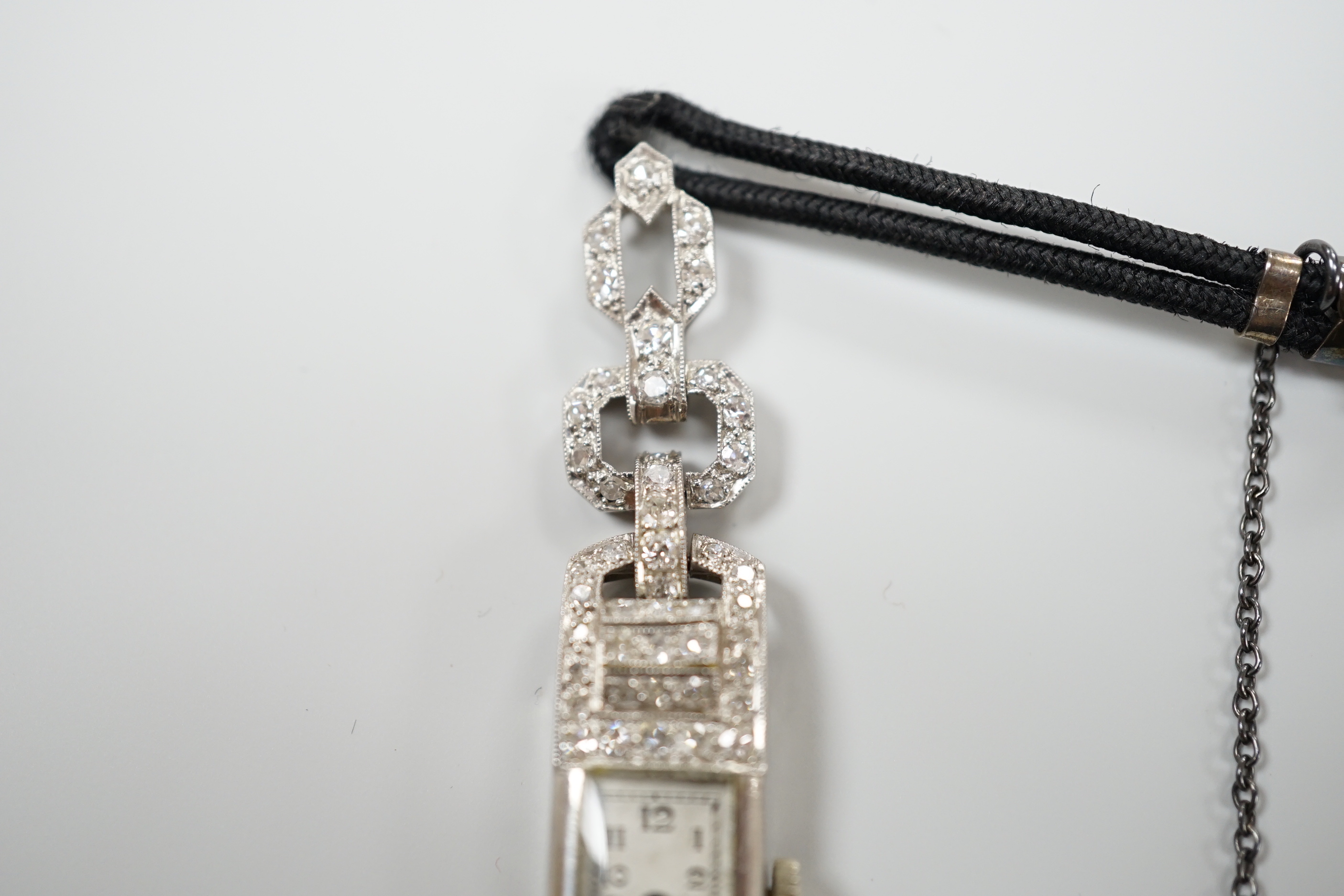 A lady's 1930's/2940's white metal (engraved All Platine) and diamond set manual wind cocktail watch, on a twin fabric strap.